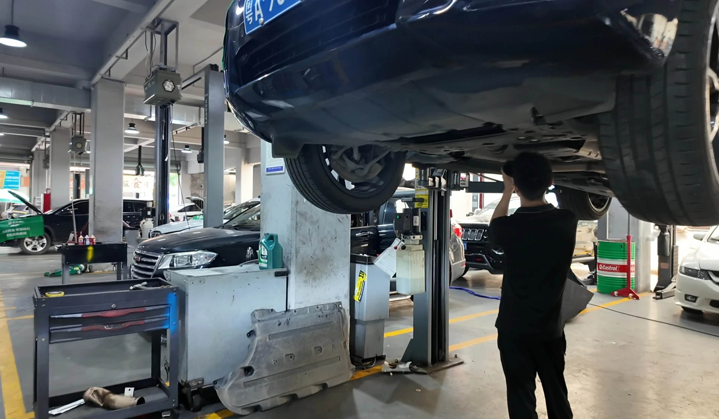 路通技师在举升车辆下进行底盘检查作业