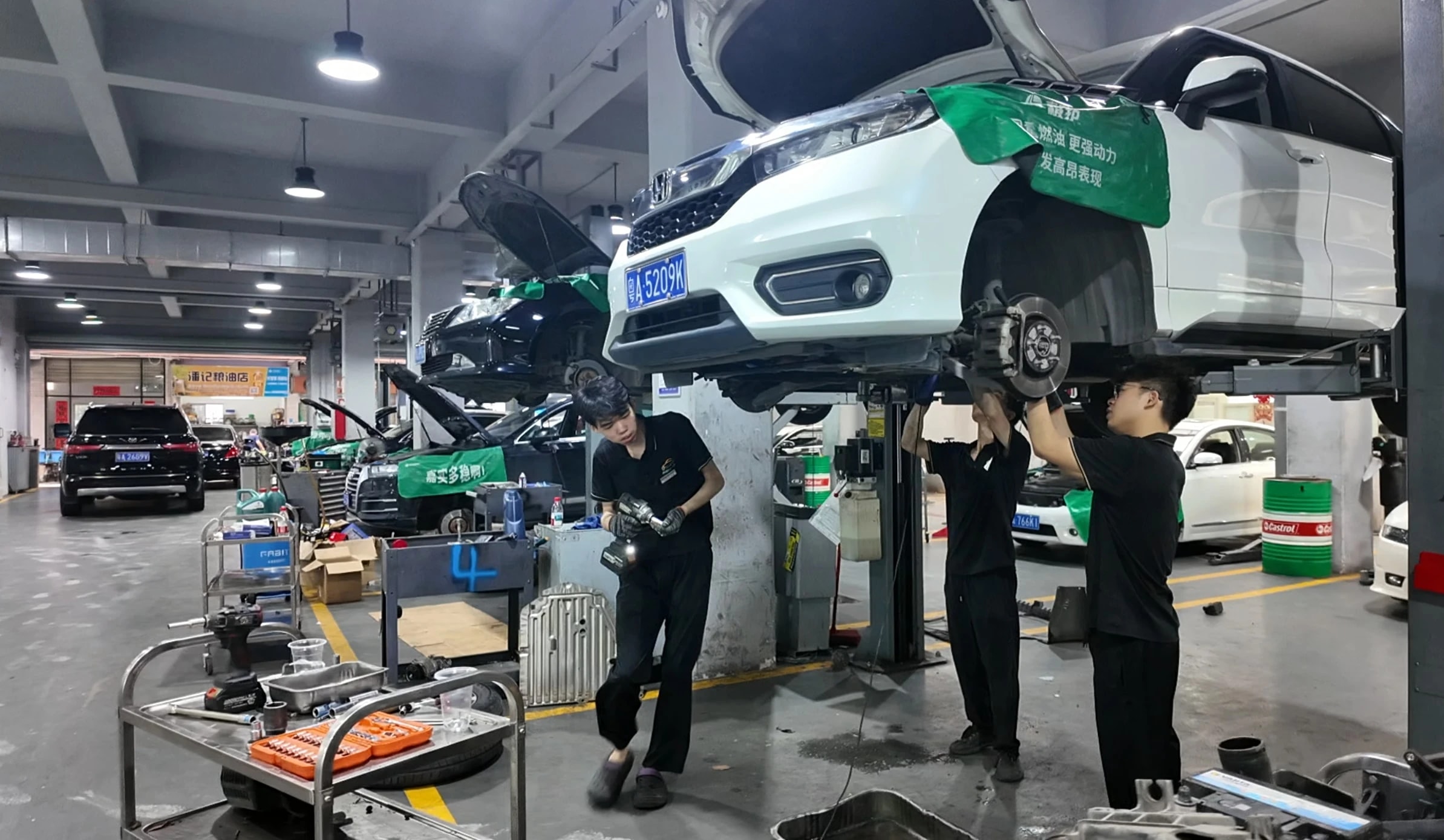 路通维修车间内,多名技师围绕举升的白色车辆协同作业